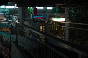 現代室內空間，擁有混凝土牆面與地板，包含設有桌椅的餐廳區、廚房，以及盆栽植物