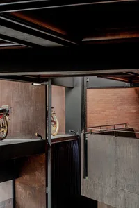 Two motorcycles on display in a showroom with a brick wall background, one red and black, one gold, in a well-lit space