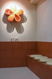 A warm and inviting cafe interior with ceramic flower decorations on a wall, adding a pop of orange color to the space