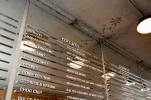 一塊繽紛的菜單看板，展示Gelato口味、餅乾與新鮮草莓，文字與圖像突顯每道甜點