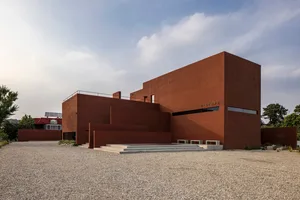 A large modern building with a red brick exterior, stone and glass elements, and a contemporary design