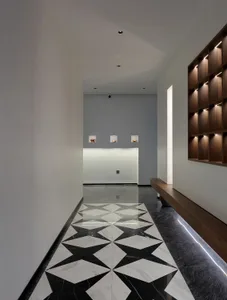A clean and organized hotel lobby with a black and white checkered tile floor, two benches, and three clocks on the wall