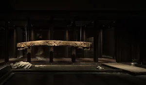 A wooden sculpture with intricate carvings on a pedestal in a dimly lit room