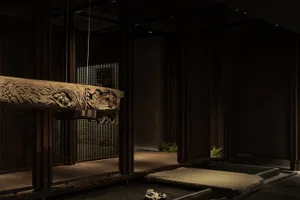 Warm and inviting room with wooden walls and floors, a large wooden table, and potted plants, featuring traditional Asian design elements