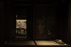 Cozy Asian-style living room with wooden walls and floors, dimly lit with two doors and three chairs