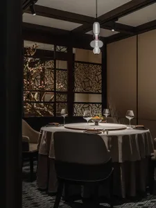 Elegant dining area with a round table, chairs, wine glasses, and food bowls, set for a special occasion