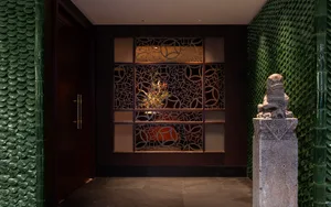 Elegant hallway with a door, glass wall, and display cases showcasing artwork and a potted plant, set against a tasteful backdrop