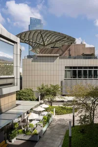 A modern building with a large dome on its roof, featuring a mix of concrete, glass, and metal materials, with a sophisticated and elegant atmosphere