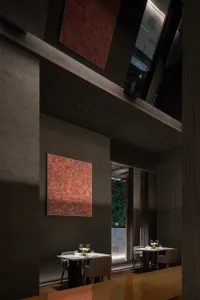Elegant dining space with marble surfaces, tables, chairs, and wine glasses, highlighted by warm lighting