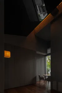 Cozy interior space with wooden walls and floors, featuring a dining table, chairs, and a potted plant