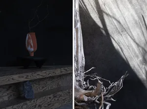 A black and white artistic representation of a tree branch next to a minimalist vase on a wooden table in a calm atmosphere