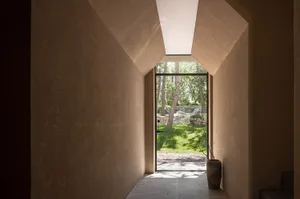 A serene home entrance with a doorway, potted plants, and a vase, surrounded by a natural atmosphere