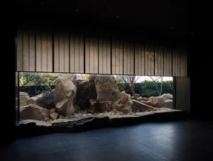 Indoor space with a rock wall and a window offering a view of the outside landscape, featuring rocks and trees