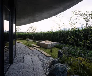 A serene outdoor garden with a stone pathway leading to a rock garden, surrounded by natural elements