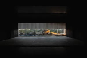Empty living room with large windows offering a view of rocks outside, receiving natural light