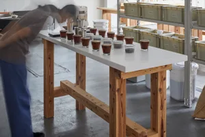A casual kitchen scene with a wooden dining table, cups, and bottles, featuring a warm atmosphere and inviting ambiance
