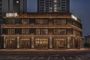 A stone exterior building with many windows, illuminated at night, with outdoor seating and a warm ambiance