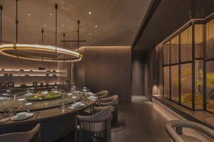 Elegant restaurant interior with wooden walls and floors, featuring multiple dining tables and comfortable seating, with decorative items and a sophisticated atmosphere