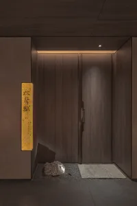 A wooden door with a brown frame, flanked by two doors, features a rock outside, creating a calm and inviting atmosphere