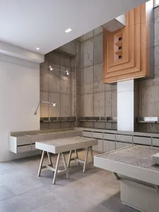 Modern showroom with concrete walls, display tables, chairs, and well-lit atmosphere