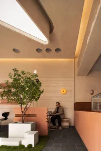 A comfortable home office with a bench and chairs, surrounded by potted plants and natural light