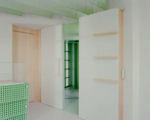 A modern hallway with white walls, green accents, two large closets, and a clean, organized atmosphere