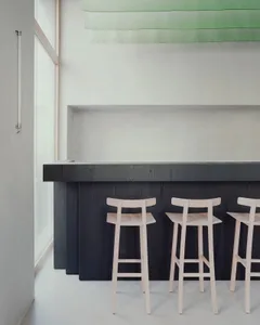 A modern bar counter with three stools in front, featuring a wooden counter and metal stools in a sleek design