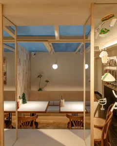 Dining area with multiple tables and chairs, potted plants, and a warm atmosphere