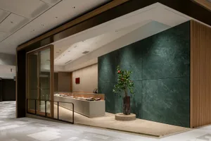 Lobby area with marble and green stone walls, a potted plant, and vases, creating an elegant and sophisticated atmosphere