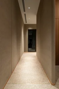 深色辦公室走廊，鋪有地毯地板、混凝土牆壁，以及通往另一房間的空曠空間