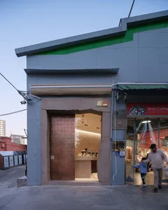 A casual coffee shop interior with wooden accents, stone walls, and a doorway leading to another room, featuring people socializing and walking around