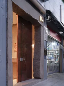 商店微暗燈光內部，通往另一房間的門道、石牆與玻璃窗