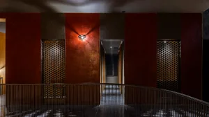 Narrow interior hallway with red walls, brown doors, and a textured brick or stone appearance