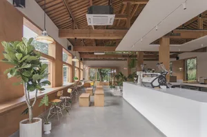 Warm and inviting restaurant interior with wooden floors and walls, featuring seating areas, potted plants, and a cozy atmosphere