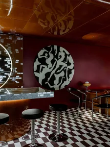 Modern bar area with a circular countertop, stools, and two chairs, creating a stylish and functional space