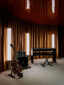 A dimly lit room with a piano and two guitars, creating a cozy atmosphere