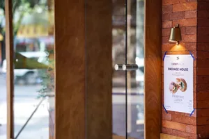 A doorway with a wooden door and two signs, one reading 'pack' in white letters, in a possibly restaurant or store setting