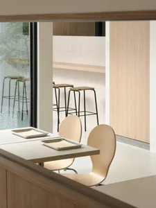 Warm and inviting restaurant interior with wooden floors and walls, featuring a dining table and chairs, and a smaller table in the background