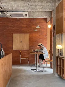 Cozy restaurant interior with a dining table, chairs, and a counter, featuring a woman sitting at the table and two cups, with a warm and inviting atmosphere