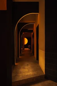 A calm and inviting indoor hallway with a black and white color scheme, featuring a large archway and smooth concrete-like walls