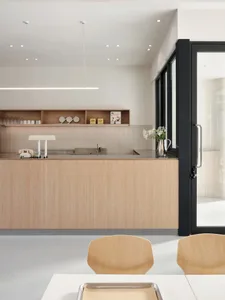 Well-equipped kitchen with wooden cabinets, countertops, and a sink, featuring two chairs, a potted plant, and various kitchen items