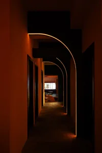 燈光柔和的走廊，配備現代極簡家具，包括長椅與餐桌，位於建築室內