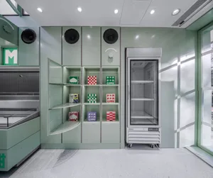 A modern kitchen with green walls, white cabinets, and a refrigerator freezer, featuring multiple shelves with boxes and a clean design