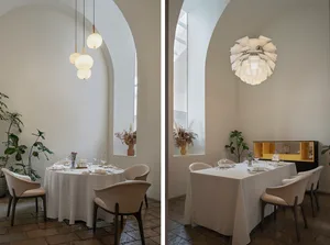 Dining area with modern chairs and tables, wine glasses, and vases, set for dinner service in a stylish restaurant