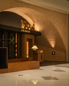 Warm and inviting restaurant interior with a wooden bench and dining table, bottles on the table, and a cozy atmosphere