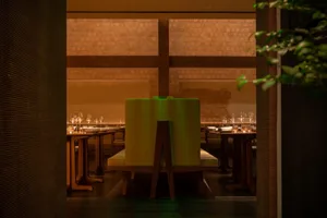 An inviting restaurant with wooden floors and walls, featuring multiple dining tables and chairs, with wine glasses on some tables