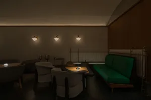 Cozy living room with a green couch, two chairs, a dining table, and a bar area, featuring wine glasses and a comfortable seating arrangement