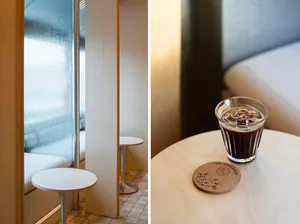 Modern bathroom with glass shower door and minimalist decor, adjacent to a dining area with a table and cup
