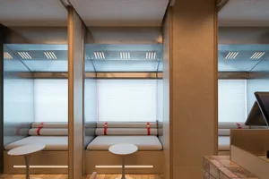 A well-lit open concept living area with wooden walls and floors, featuring a central table and two benches, creating a comfortable and inviting atmosphere