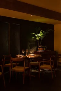 A warm and inviting dining area with a wooden table and chairs, wine glasses, bowls, and cups, suggesting a space for meals and drinks